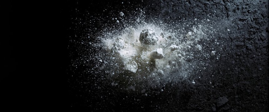Explosive scattering of white powder and granite rocks over a black textured backdrop
