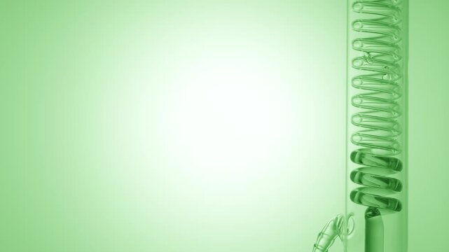 Transparent green liquid flows through a vertical coil lab condenser, filling the coiled glass tube on the right side of the frame, leaving the left side as copy space on green ramp background