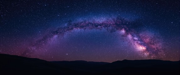Obraz premium Expansive space background capturing purple Milky Way and stars over gentle hills at summer night