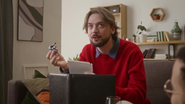 Close up shot of game master sitting behind screen, holding action figure and explaining rules of tabletop RPG to his friends in cozy living room