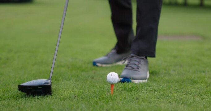 Hands, golf ball and driver or tee, sports and competition on grass, challenge and tournament. Person, athlete and ready for game, practice and hobby or recreation, action and equipment for match