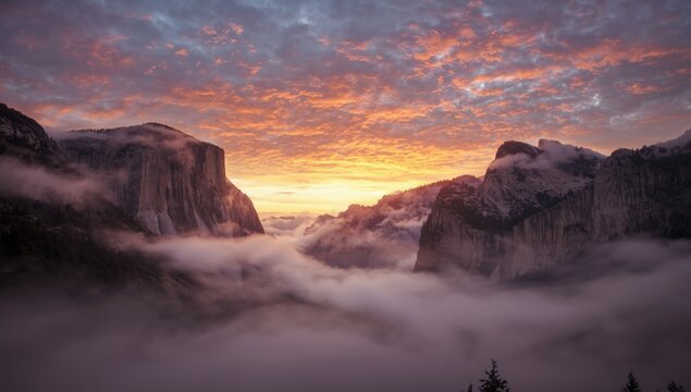 Dynamic colorful sunset sky with layers of fog in a deep valley and tall peaks