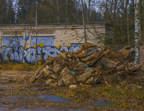 Debris cleanup ongoing. Site with scattered wreckage. Disorderly pile of rubble near graffiti wall