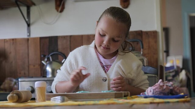 Young girl with ponytail plays with Play Doh at home kitchen table