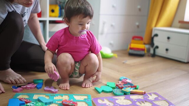 baby daughter plays with toys on the floor develops fine motor skills. Mom plays with her baby daughter, teaches her to put pictures into slots. happy family kid dream concept lifestyle