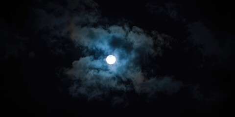 Obraz premium full moonlight filtering through moving clouds against dark night sky