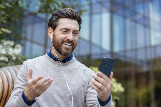 Happy man having video call using smartphone outdoors