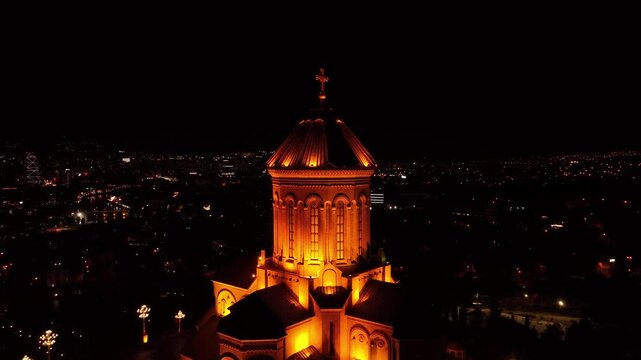 Epic nighttime drone orbit around Holy Trinity Cathedral. Golden illumination and dramatic city lights create a breathtaking visual scene.