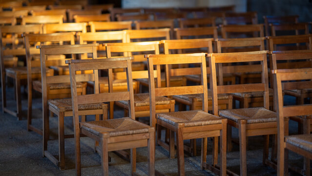 Rows of vintage wooden church chair lined up in warm interior light