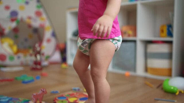 baby gets to a his feet and takes his first steps. happy family kid dream concept. baby among children's toys gets up from the floor takes his first lifestyle steps learns