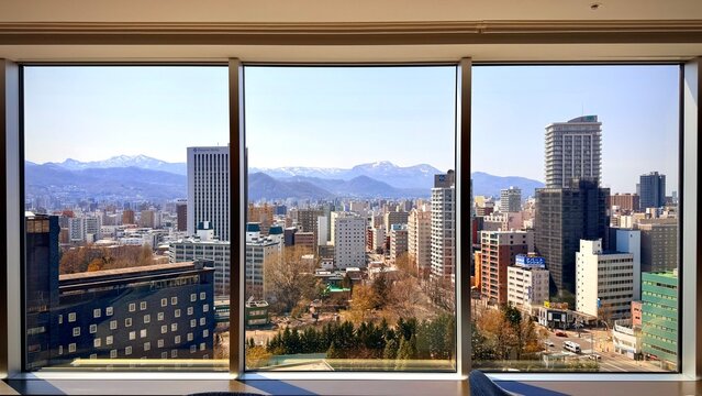Stunning view of Sapporo cityscape and Nakajima Park through a luxury hotel floor-to-ceiling window, Hokkaido.