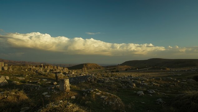 Expansive view of archaeological stones with layered hills and dramatic cloudscape