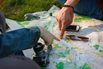 Young couple planning a hiking route with a paper map and vintage camera. © Kyiv Stock