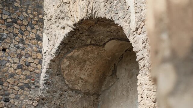 Close architectural detail of a vaulted Roman recess in Pompeii, highlighting cracked plaster, curved form, and ancient construction inside the archaeological ruins.