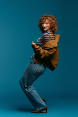 Stylish young woman showcases her playful fashion sense against a vibrant blue backdrop