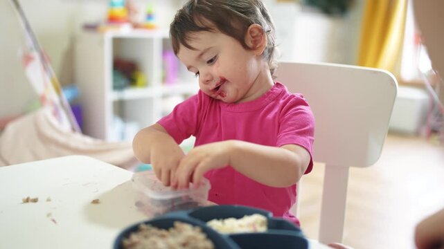 grimy baby eats at the table. baby learns to eat develops fine motor skills gets his face dirty. happy family kid dream concept. baby blond daughter lifestyle eats dirty