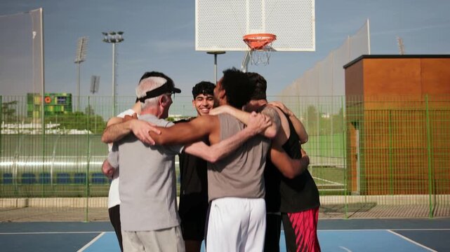 Multigenerational and multiethnic basketball team celebrating together with hugs and high fives