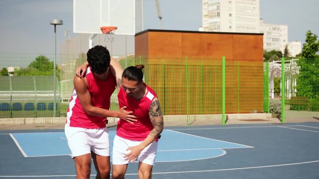 Young man assisting his injured teammate walking off the basketball court during a game