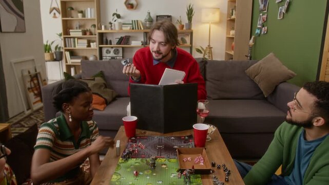 Zoom out shot of game master explaining rules of tabletop RPG to group of his friends, enjoying board game night in cozy living room