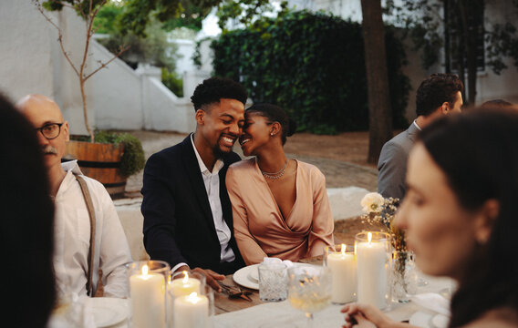 Couple sharing a loving moment at an elegant outdoor wedding with friends