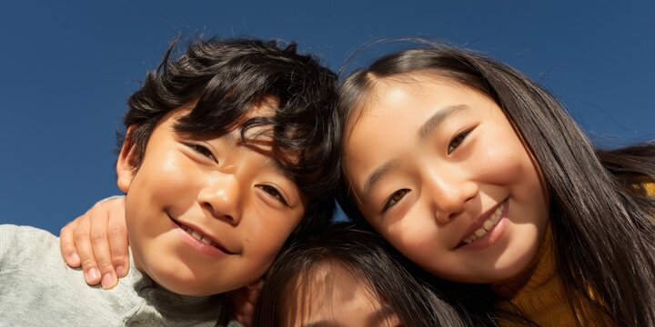 Two children smiling together while posing under blue sky