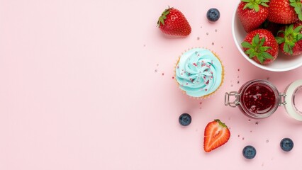 Fototapeta premium Blue Frosted Cupcake with Strawberries on Pink Background. Sweet dessert composition featuring blue frosted cupcake, strawberries, blueberries, and jam on a pastel pink background with copy space