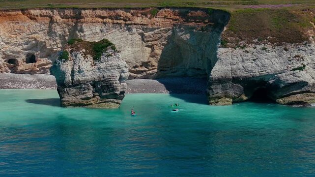 People paddleboarding in turquoise sea by chalk cliffs on Isle of Wight
