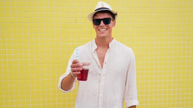 Smiling young man dancing with cocktail on summer vacation