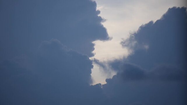 Dark clouds gather across the sky as sunlight filters through from behind, signaling changing weather conditions and the possibility of rain soon.