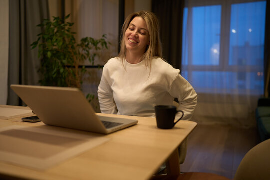 Freelancer smiling while easing lower back tension at work