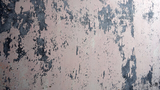 Heavily weathered wall with scattered peeling paint exposing dark underlayers.