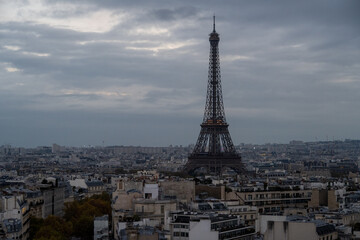 Fototapeta premium Eiffel Tower over Paris rooftops under cloudy sky
