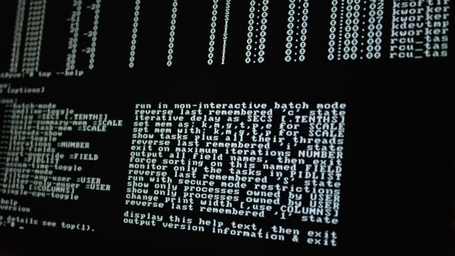 Static close up of a computer monitor displaying a command line interface. A system monitoring utility shows a process list and a white text help menu on a black background. Fixed camera perspective