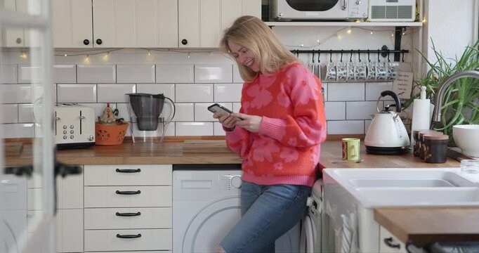 Mature woman, phone and laughing while typing or reading funny message on social media or mobile app. Happy female model person with a coffee cup and smartphone for communication or chat in kitchen