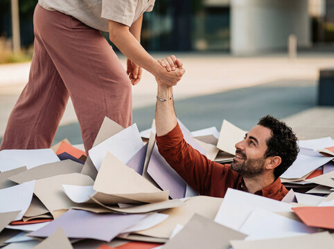 Person rescuing coworker from overwhelming pile of paperwork