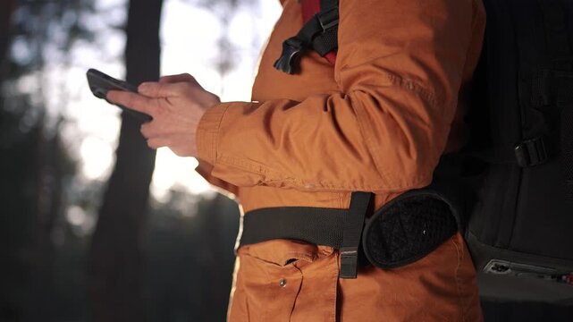 travel navigation. man tourist looking for a way in a smartphone navigation in winter in a forest park. male hacker navigates in the forest navigation looking for a way close-up in winter in park