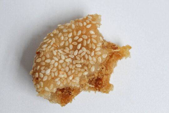 Onde-onde, is a Indonesian sesame ball, with grated coconut and red sugar filling. The remaining onde-onde that has only been bitten half way. Isolated on white background