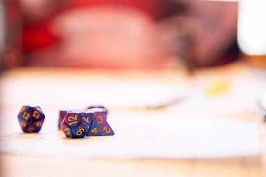 2 purple polyhedral gaming dice with gold numbers rest on a wooden table with generous copy space, symbolizing tabletop role-playing games, strategy, luck, and imagination.