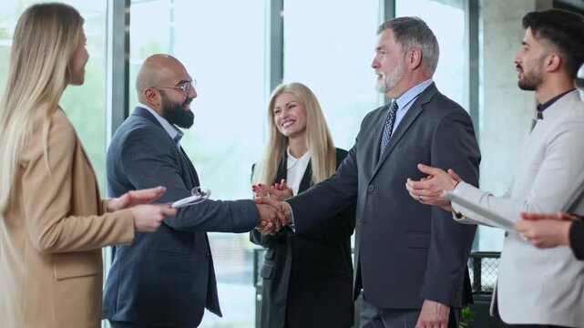 Five professionals shake hands in a bright office