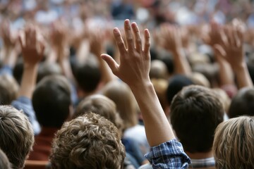Fototapeta premium A person raises their hand in a crowd of people, signifying participation, agreement, or a question.