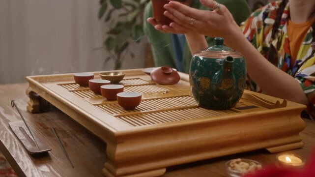 Close up low angle shot of group of unrecognizable people having tea ceremony at home in cozy lving room