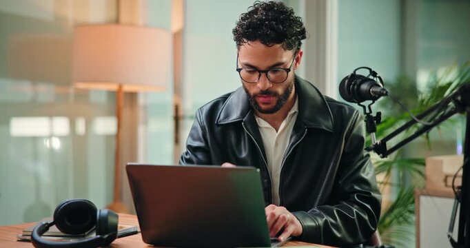 Happy, laptop and man with mic in studio for podcast, editing broadcast and recording with tech. Content creation, production and person on computer for audio, radio presenter and hosting show