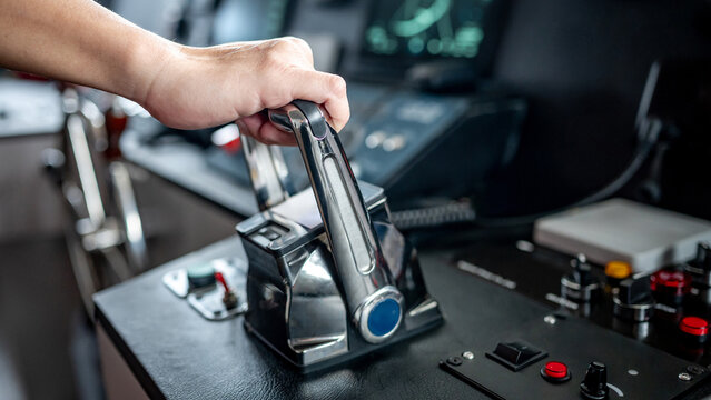 Captain hand holding throttle control or engine control lever on boat dashboard with GPS navigation and marine radar in wheelhouse or ship bridge. Speed adjustment instrument for seafaring technology