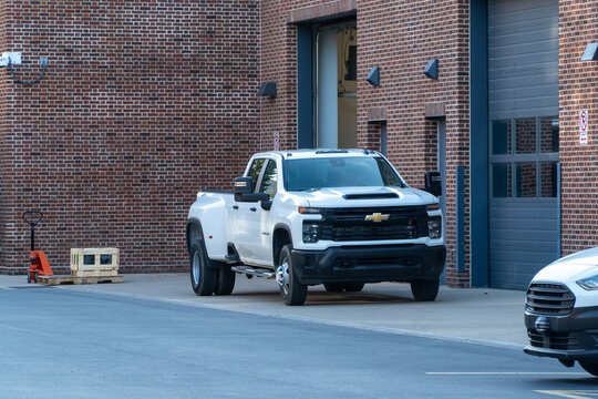 Powerful white Chevrolet Silverado 3500 HD dually pickup truck parked outside a modern brick commercial building with garage doors, showcasing heavy-duty utility and strength for work and transport.