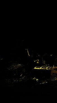 Several objects are scattered on a dark surface. The items vary in shape and size, creating an unclear but intriguing scene. Light reflects off some surfaces, giving a glimpse into the arrangement.