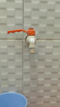 Orange Plastic Water Faucet Mounted on Ceramic Tile Wall