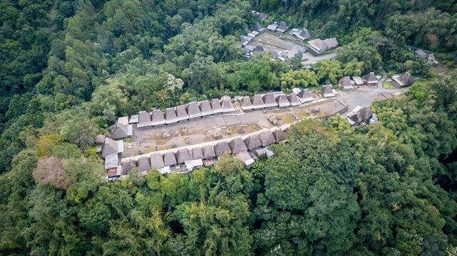 Aerial view of Bena Traditional Village with iconic thatched roof houses arranged in parallel rows surrounded by dense tropical forest, Kecamatan Jerebuu, Nusa Tenggara Timur, Indonesia.