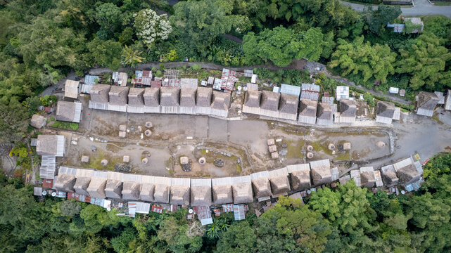 Aerial view of Bena Traditional Village with its iconic thatched roof houses arranged in rows surrounded by lush tropical forest in Kecamatan Jerebuu, Nusa Tenggara Timur, Indonesia.
