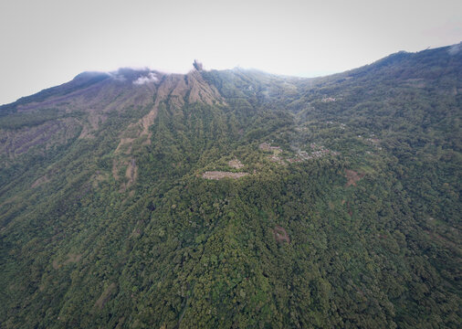 Aerial view of Bena Traditional Village on a lush mountain ridge surrounded by dense tropical forest and volcanic peaks Kecamatan Jerebuu, Nusa Tenggara Timur, Indonesia.