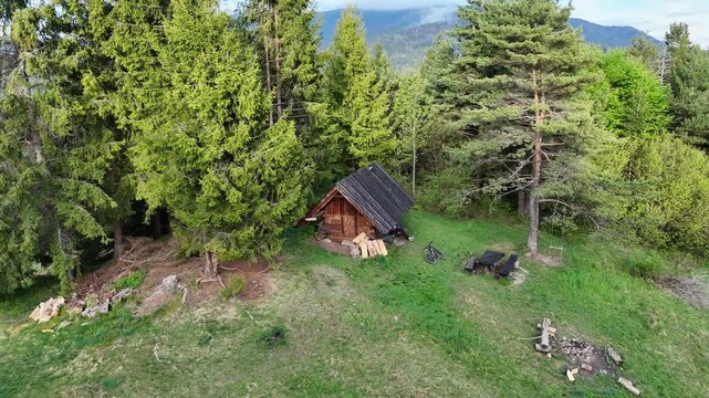 Aerial Drone Spiral Helix Shot Rising Above Rustic Forest Shelter with Fireplace in Spring Mountain Forest